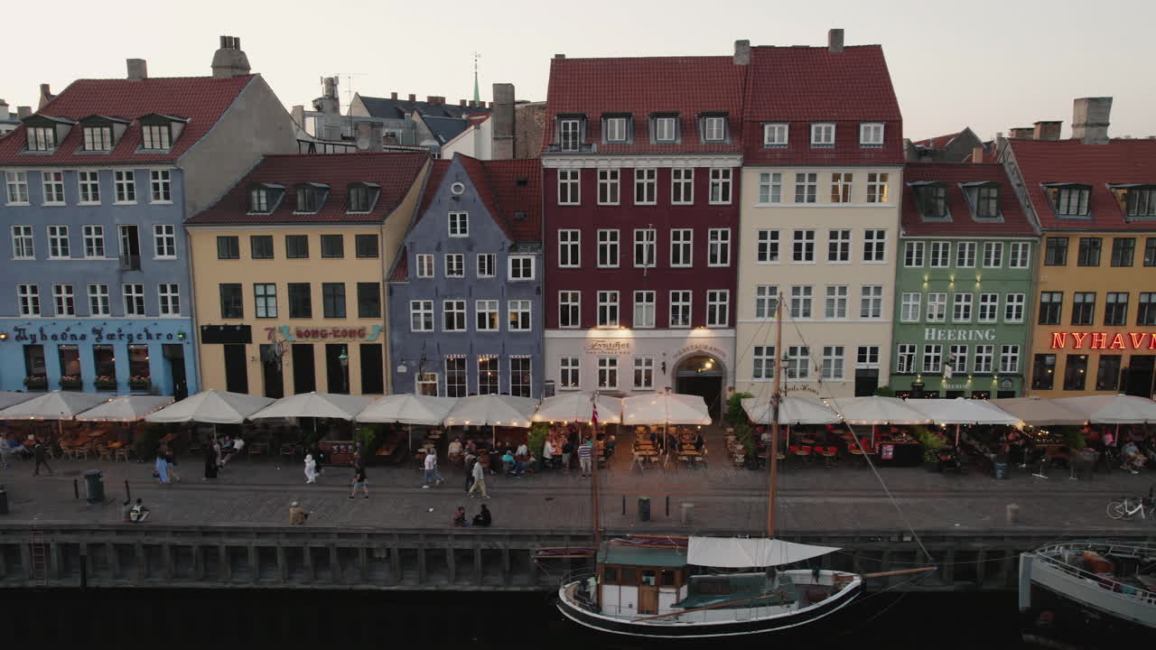 experimenta la encantadora puesta de sol sobre nyhavn, copenhagen, donde la gente se reúne, y los barcos navegan por el encantador canal