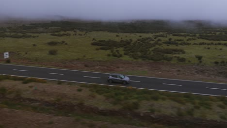 aerial view of cars driving on road near pico do areeiro, madeira, portugal, during a foggy day. tracking shot