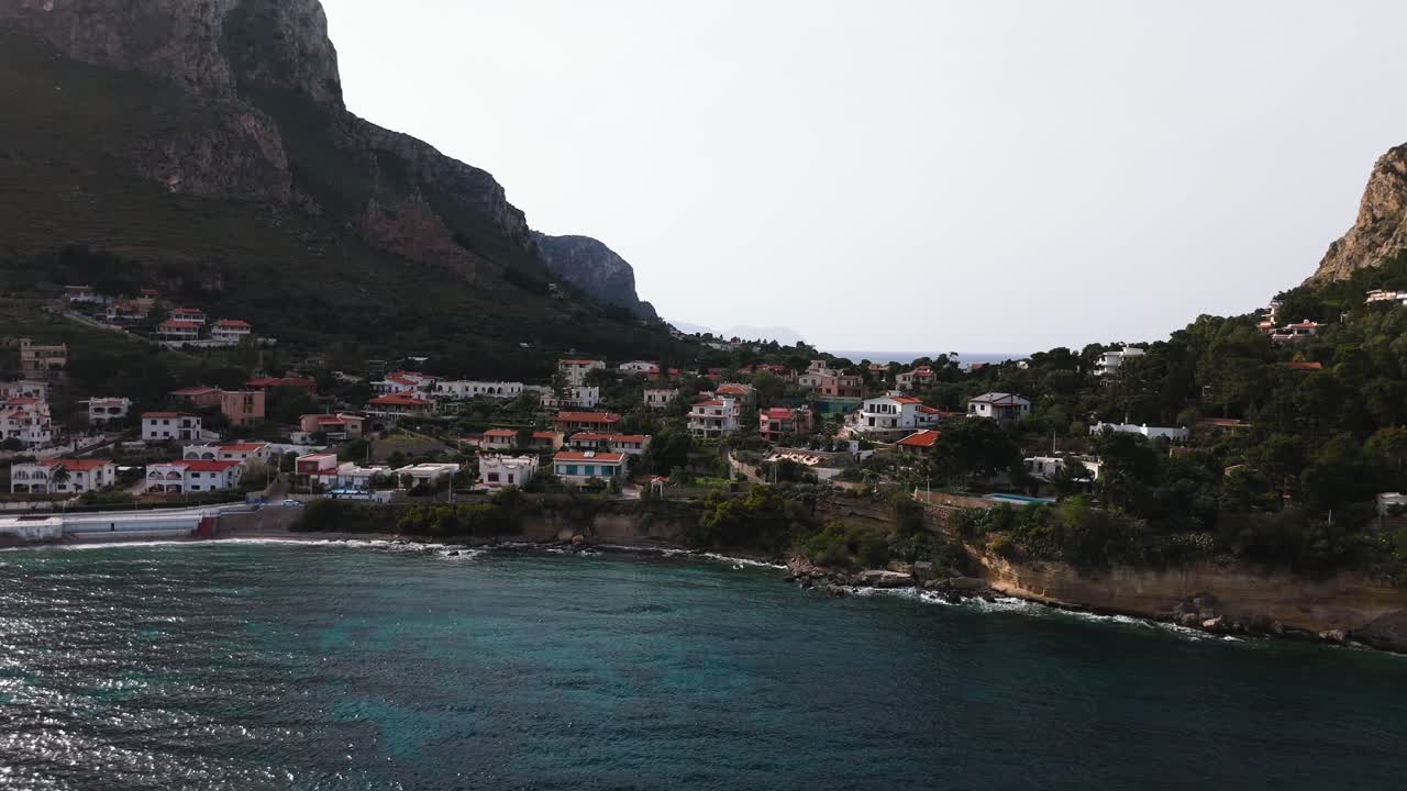 Slow motion drone clip flying over coastal houses between Capo Zafferano and Sant Elia near Palermo Sicily with turquoise sea and rugged shoreline