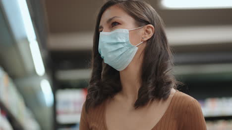 a young woman in a supermarket in a protective mask chooses milk and chilled foods