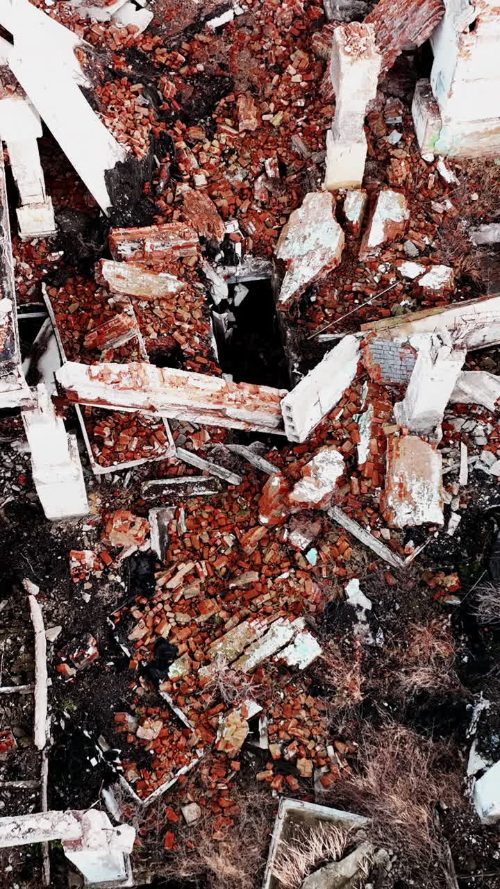 Collapsed ruins of the old building. Bricks, stones and pieces of concrete left after the house bombing. Aerial view. Vertical video