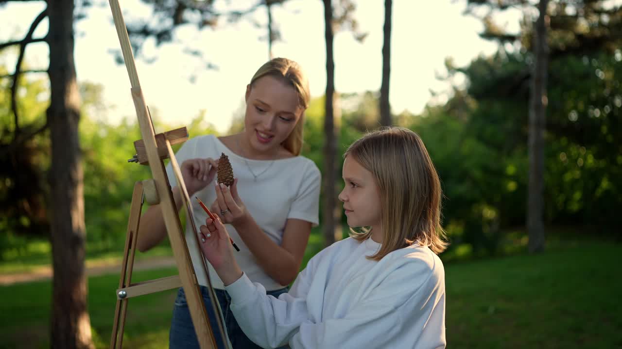 십대 소녀 는 야외 에서 소나무 어리 를 그리는 것 을 배우고 있다