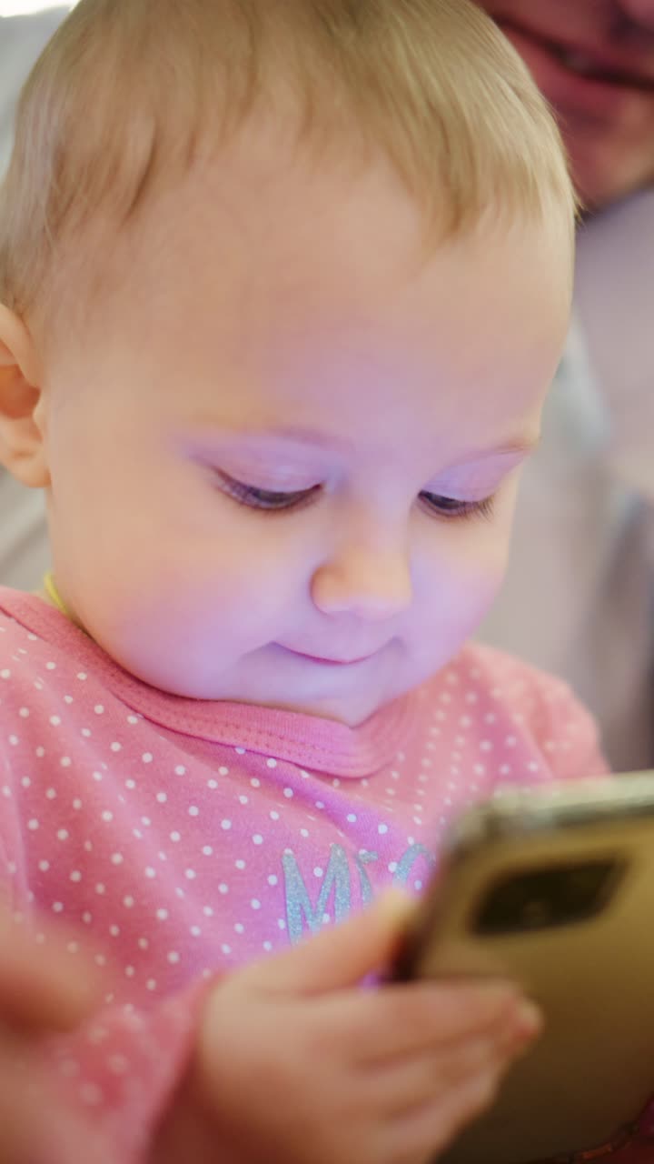 Bebé curioso absorto con un dispositivo móvil, capturando la fascinación y la interacción entre los niños pequeños y la tecnología en un ambiente interior acogedor