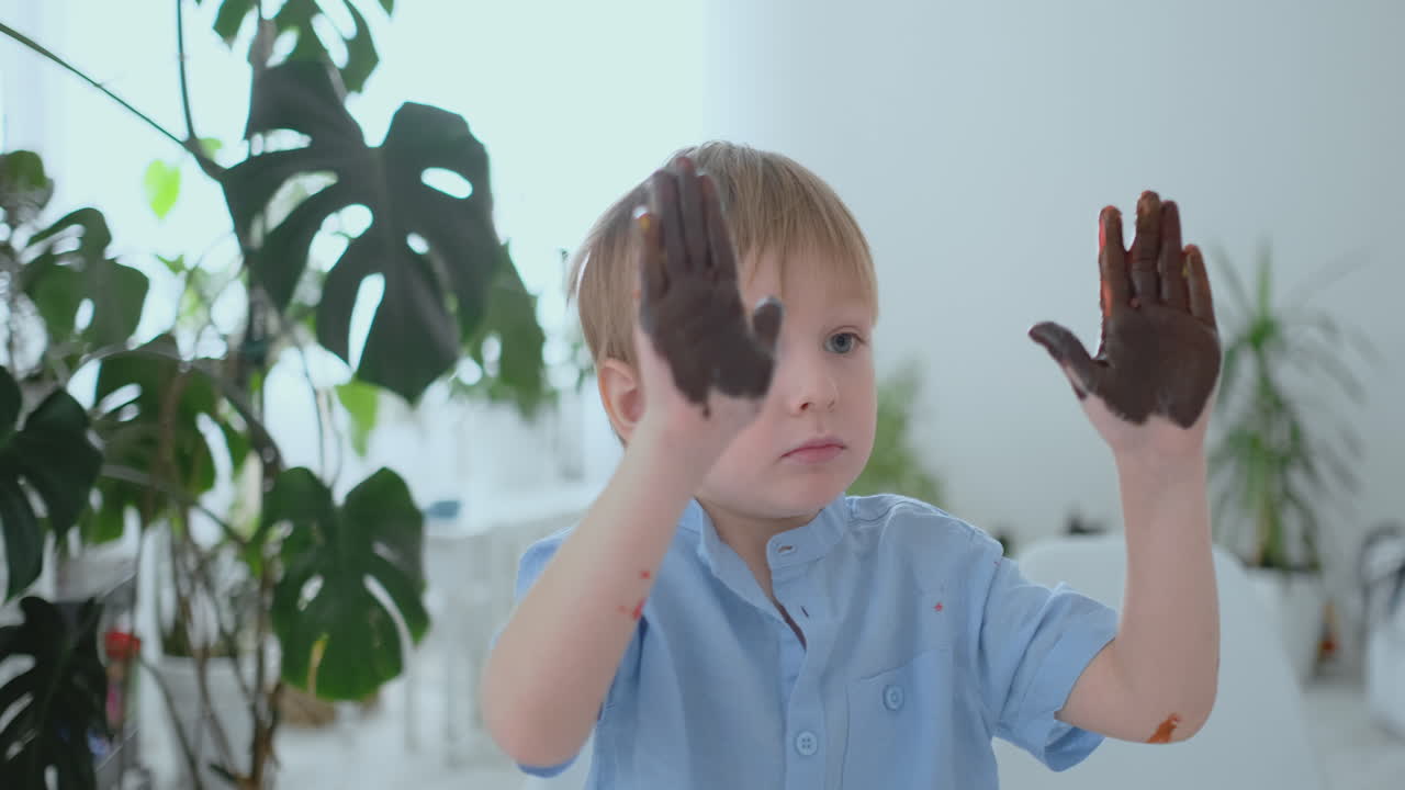 мальчик оставляет отпечатки рук на бумаге с помощью рывка. рисует пальцы с помощью pomuschiyu красок. развитие творческих навыков у детей