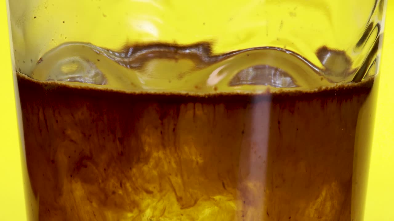 투명한 유리, 노란색 배경, 매크로 샷 가까이에서 인스턴트 커피 가루가 떨어지고 뜨거운 물에 녹는 매크로 샷