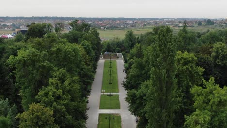 aerial view of sidewalk going through park surrounded by trees leading to packed field of tents at a music festival