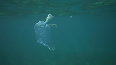 bolsa de plástico flotando bajo el agua con reflejos de luz