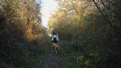 an asian woman and her dog walking into a dark path