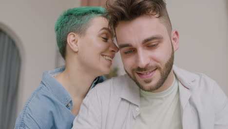 close-up view of caucasian young couple talking and hugging sitting on sofa at home