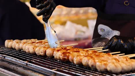 vendor grilling sausages at bangkok street food stall