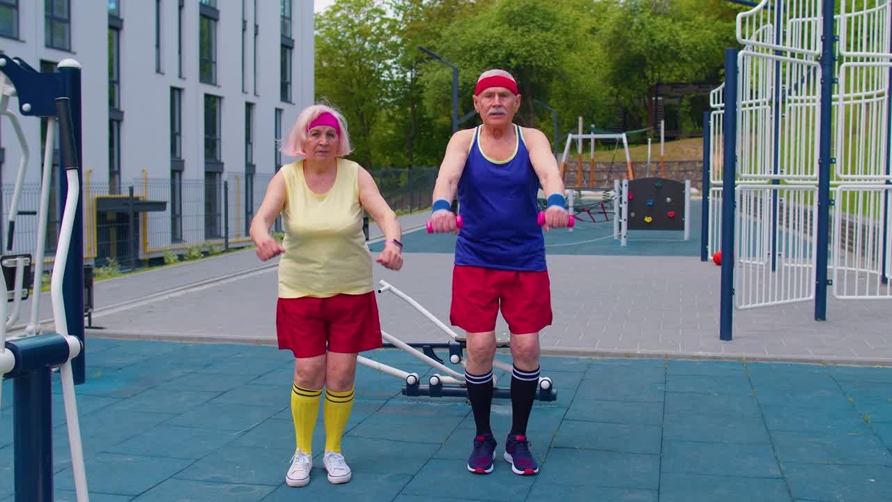 Senior man woman doing active training stretching muscles squatting fitness exercising on playground