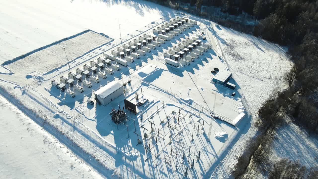 Široký letecký záběr odhaluje zasněžený velkokapacitní bateriový park a podpůrnou rozvodnu zajišťující spolehlivé dodávky obnovitelné energie.