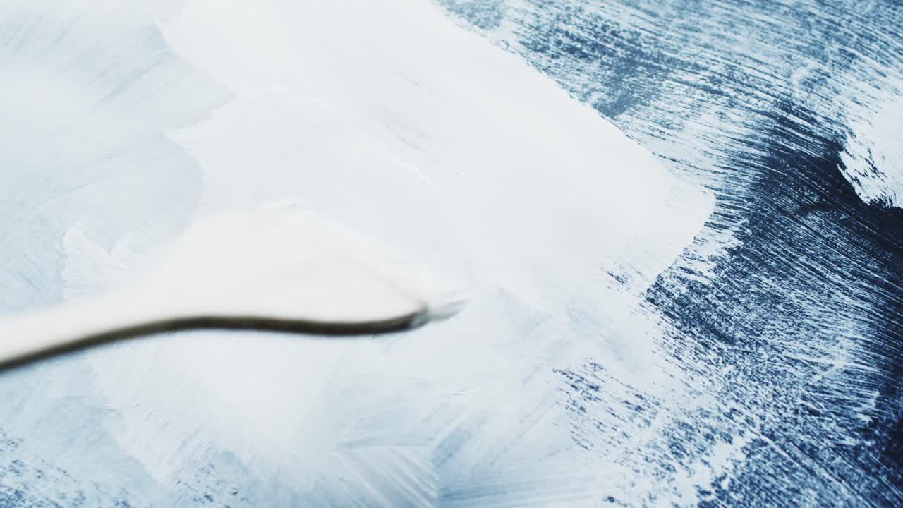 con el pincel en la mano y pintando rayas con pintura blanca sobre fondo negro, cámara lenta