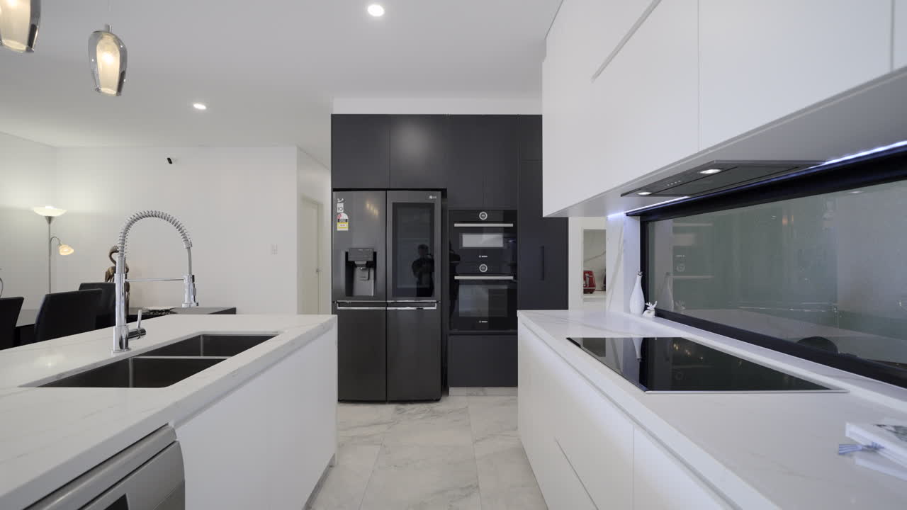 cocina moderna y lujosa contemporánea banco de mármol blanco iluminación colgante pisos de baldosas de mármol pared negra con elegantes electrodomésticos negros refrigerador almacenamiento de cocina blanco electrodomésticos rojos