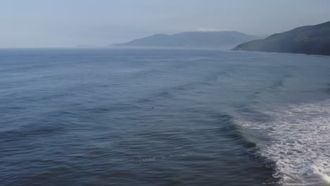 aerial: male surfers relaxing on surfboards behind breaking waves, mexico