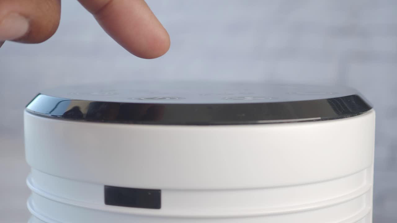 persona presionando el botón en un dispositivo blanco