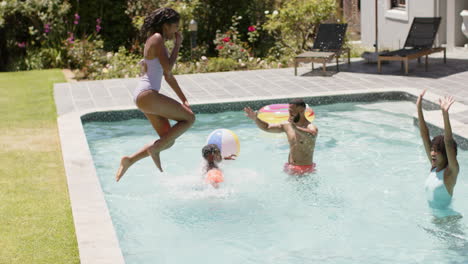 hijo y hija afroamericanos saltando a la piscina con padres felices, cámara lenta