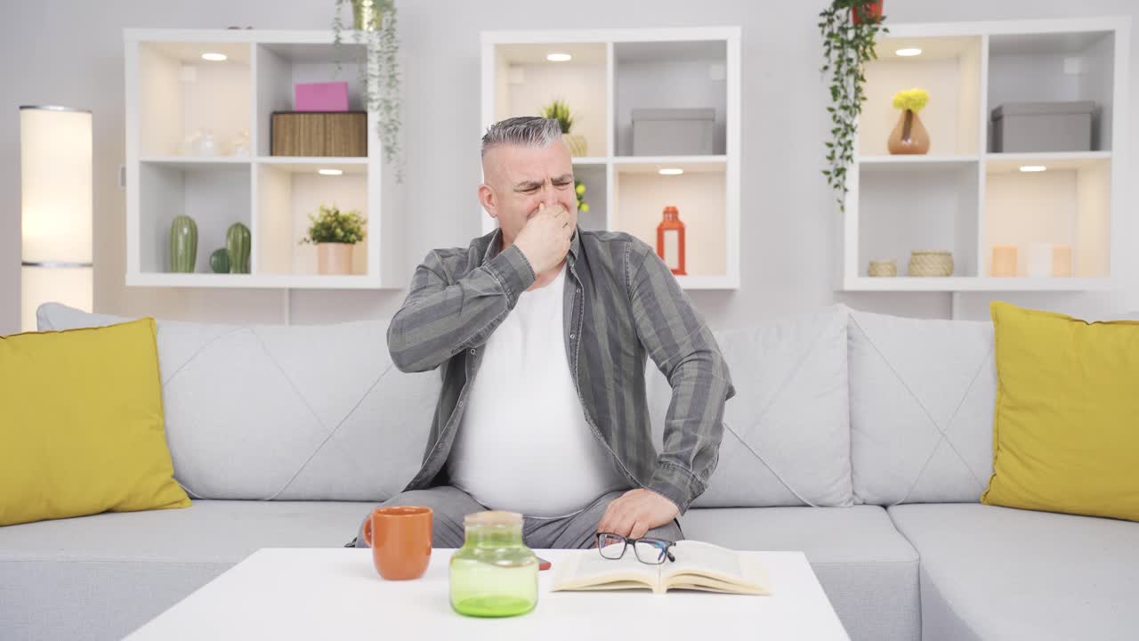 The old man who smells bad odor is disturbed and disgusted.