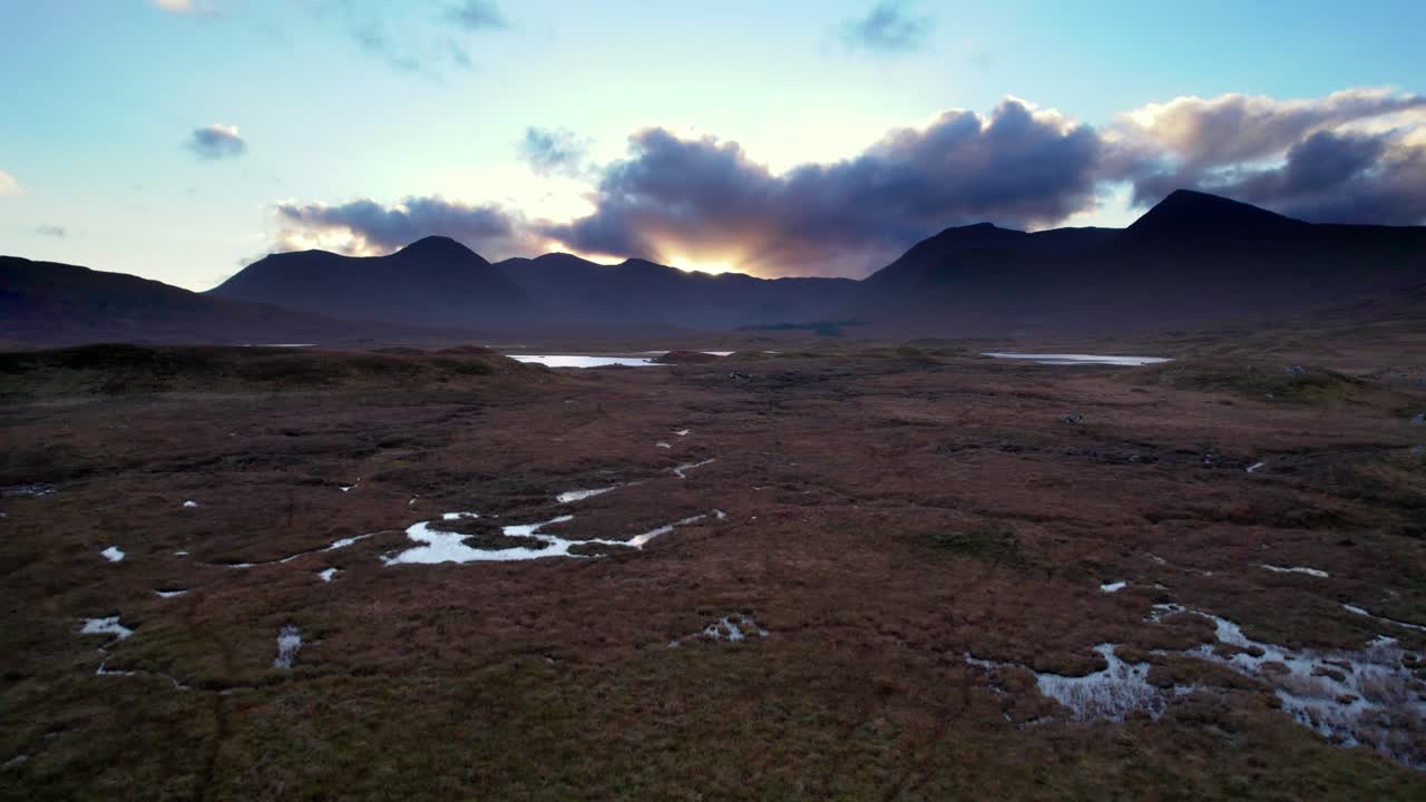 해가 질 때 지평선에 민물 호수와 어두운 산을 드러내기 전에 이탄 습지의 표면에 낮고 가깝게 날아가는 공중 드론 영상