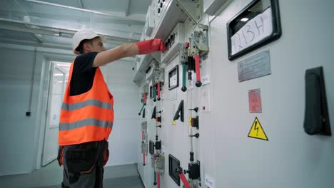 el ingeniero eléctrico que trabaja comprueba la tensión de corriente eléctrica y la sobrecarga en la parte delantera del gabinete del centro de carga o de la unidad de consumo para el mantenimiento en la sala principal del sistema de distribución de energía.