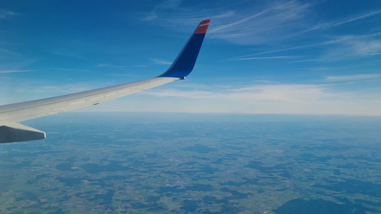 Aerial view over Eastern Europe from an airplane on a clear day, with the wing visible against blue skies, capturing the essence of travel and modern tourism