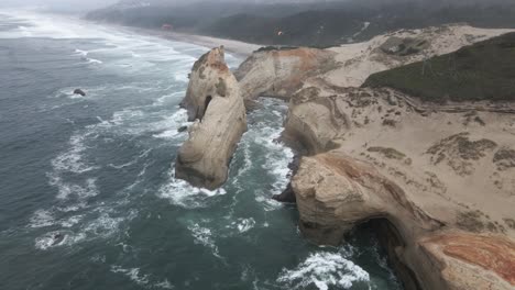 dos parapentes volando sobre el cabo kiwanda una formación rocosa fuertemente erosionada por el océano, aérea