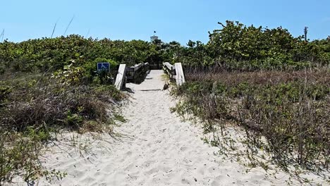 Caminando-Por-La-Arena-Hacia-El-Puente-De-Madera-Para-Discapacitados-En-La-Playa,-Cocoa-Beach,-Florida