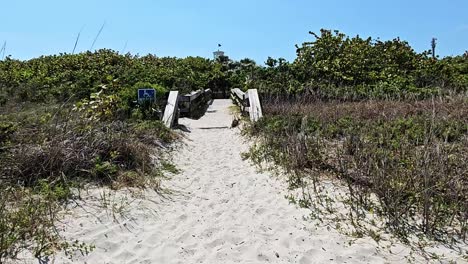 caminando por la arena hacia el puente de playa de madera para discapacitados, cocoa beach, florida