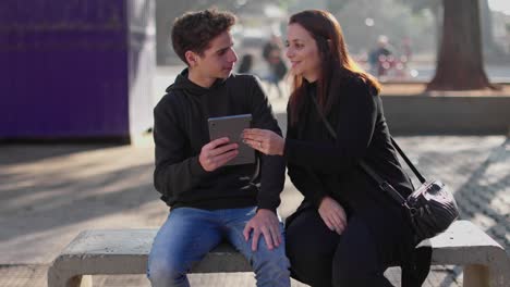 people interacting with a tablet on a park bench