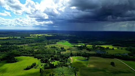 dark storm clouds flow over green landscape and raining, aerial view