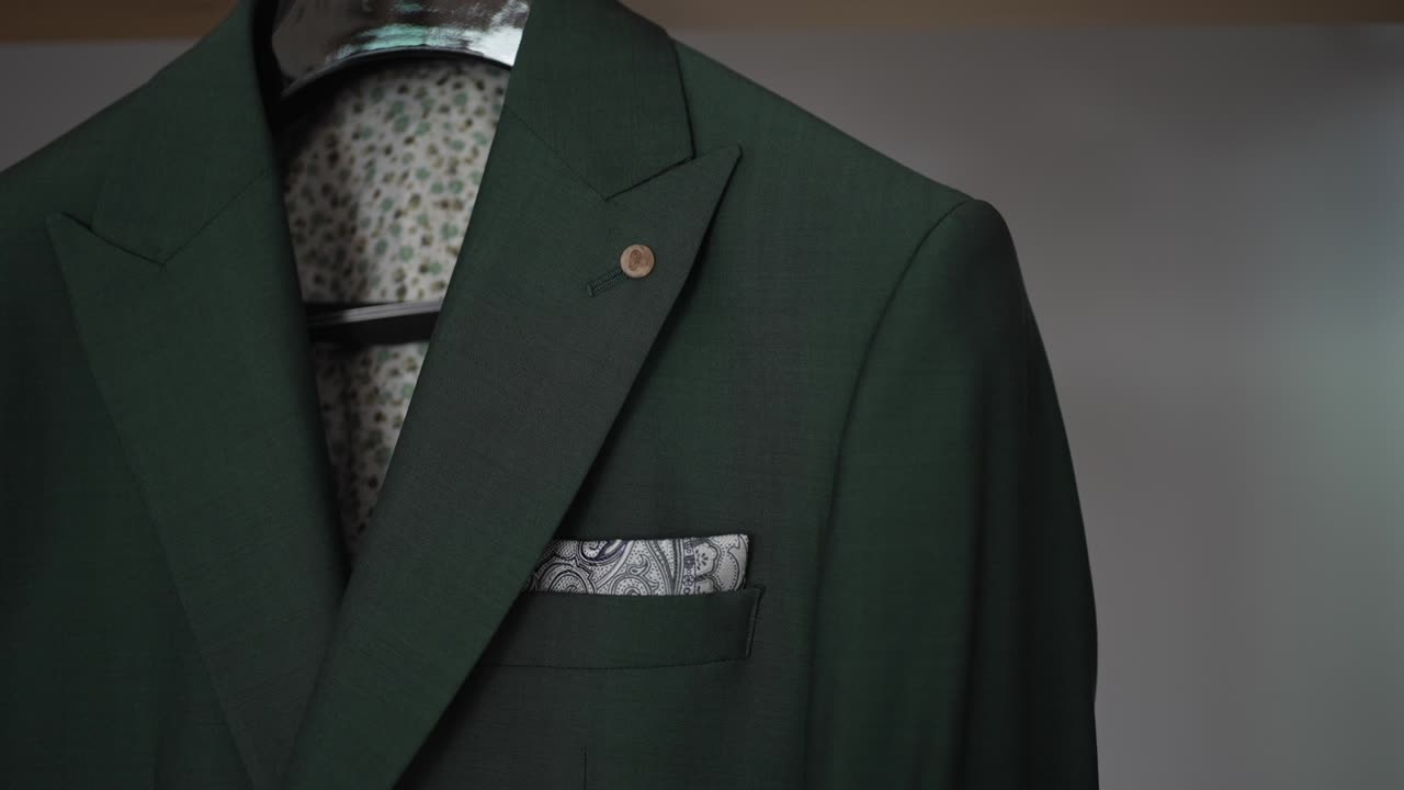 Green suit jacket with a patterned pocket square, neatly displayed on a hanger