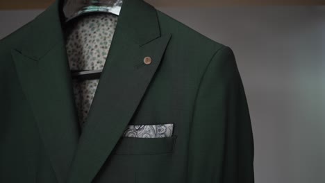 green suit jacket with a patterned pocket square, neatly displayed on a hanger