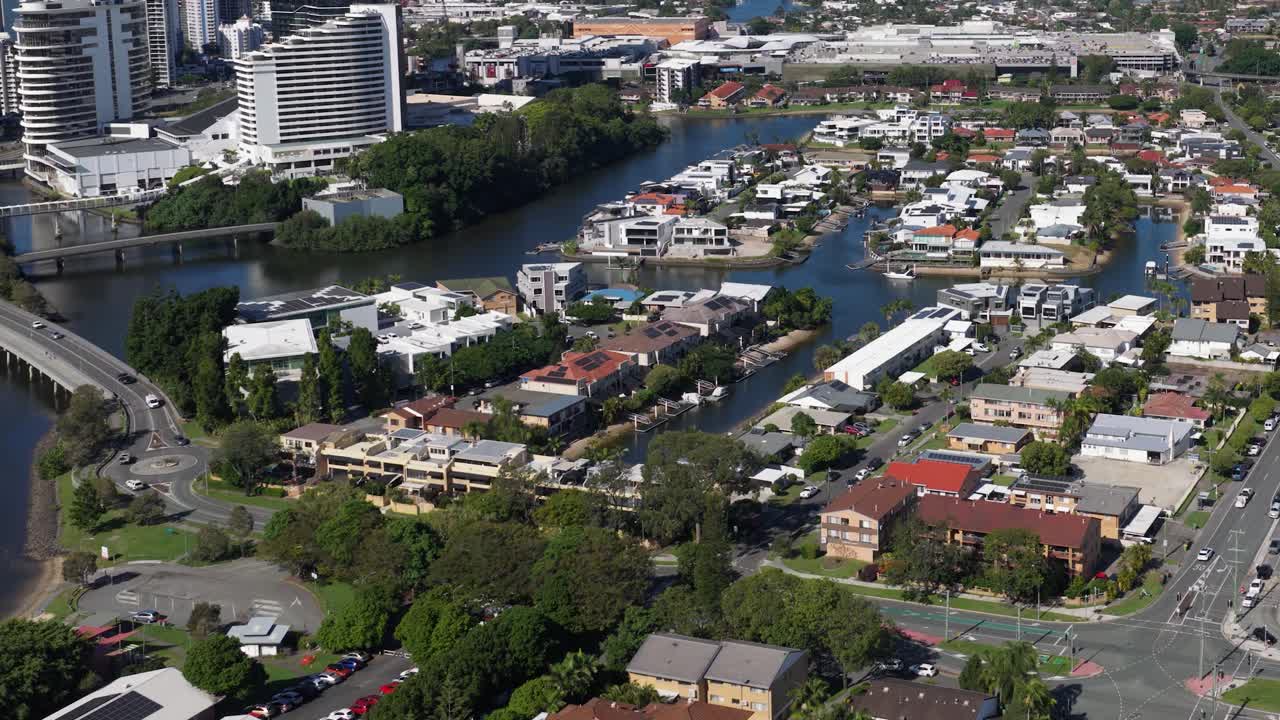 Aerial footage captures a vibrant urban neighborhood with canals, showcasing residential architecture and lush greenery under bright daylight