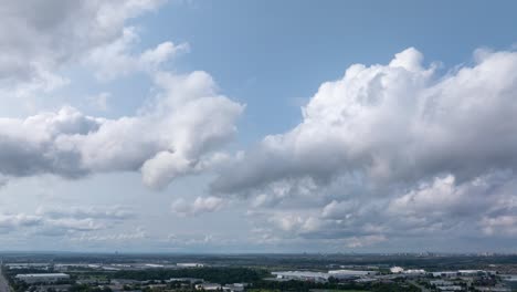 timelapse of fluffy clouds moving across a bright blue sky over an industrial landscape