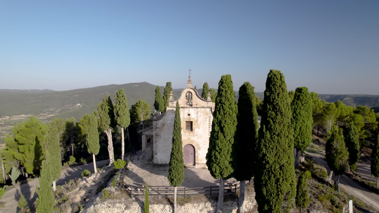 스페인 의 나무 들 사이 에 있는 언덕 꼭대기 에 있는 길 을 가로지르는 고향 의 꼭대기 에 있는 작은 종탑 에 접근 하는 전면 수준 의 전망