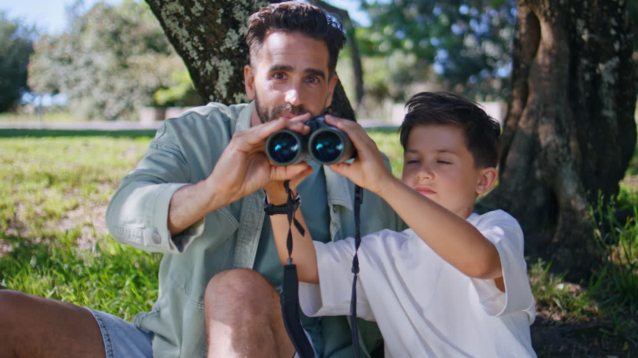 Closeup family enjoying birdwatching looking binoculars nature. Boy man bonding