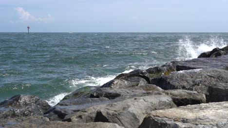 the ocean waves breaking in the rock jetty