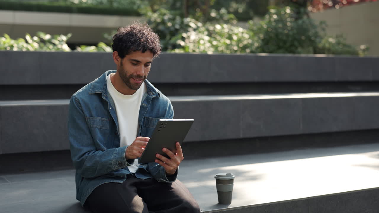 Young Man Using Digital Tablet Outdoors with Coffee