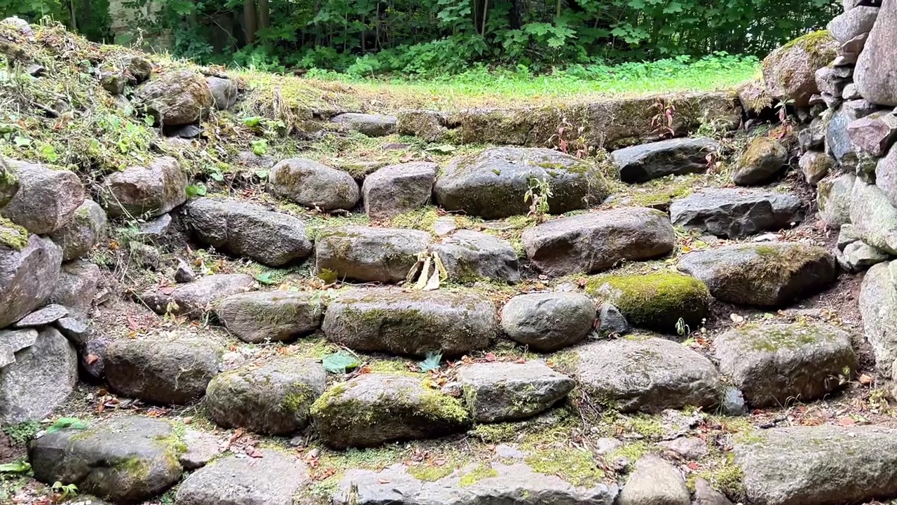 Ground-level view looking outward through an ancient stone doorway to cobble steps and a rock wall. Ideal for historical documentaries, travel, and architectural media.