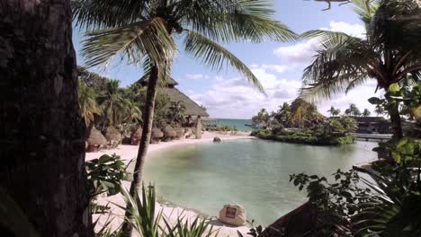 revealing shot if an inlet beach in mexico with a large palapa in the background