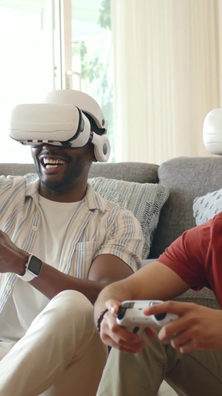 Uomo con visore VR bianco sul divano che gioca in VR con controller bianchi, alzando il pugno dopo aver segnato.