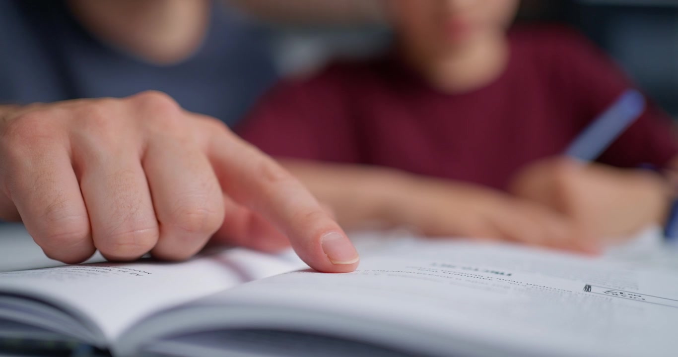 Mano di adulto che guida l'apprendimento di un bambino su un libro
