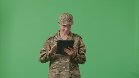 asian man soldier using a tablet while standing in the green screen background studio