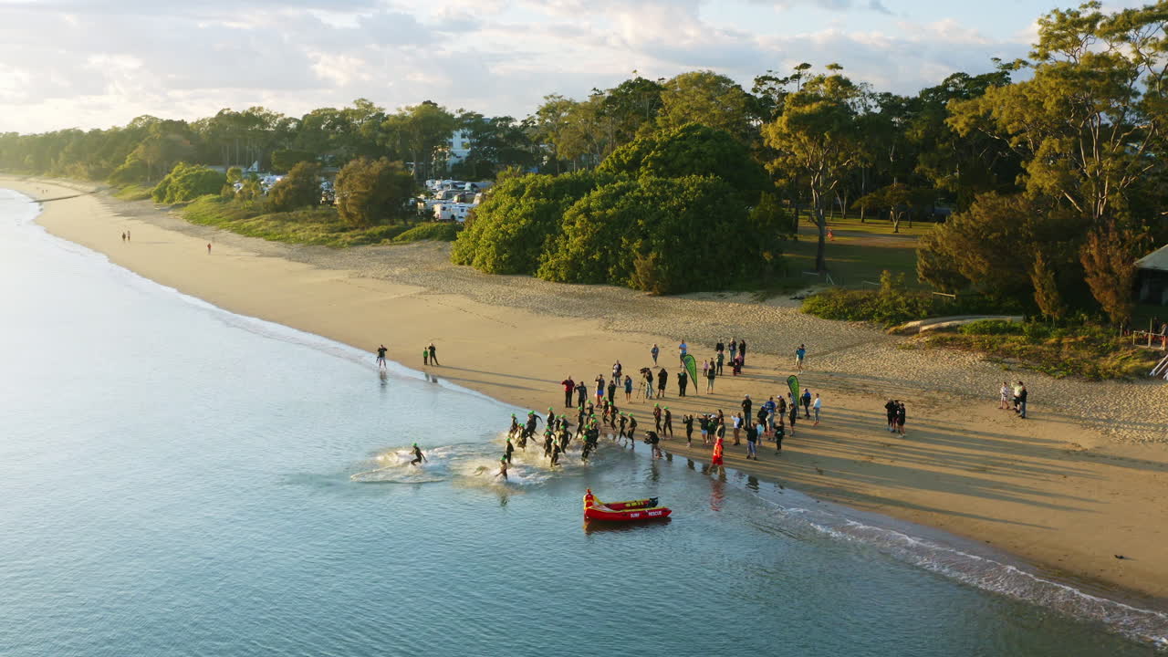 수영 경기를 위해 바다로 뛰어드는 운동 울트라 레이서 위의 공중 드론, 4k