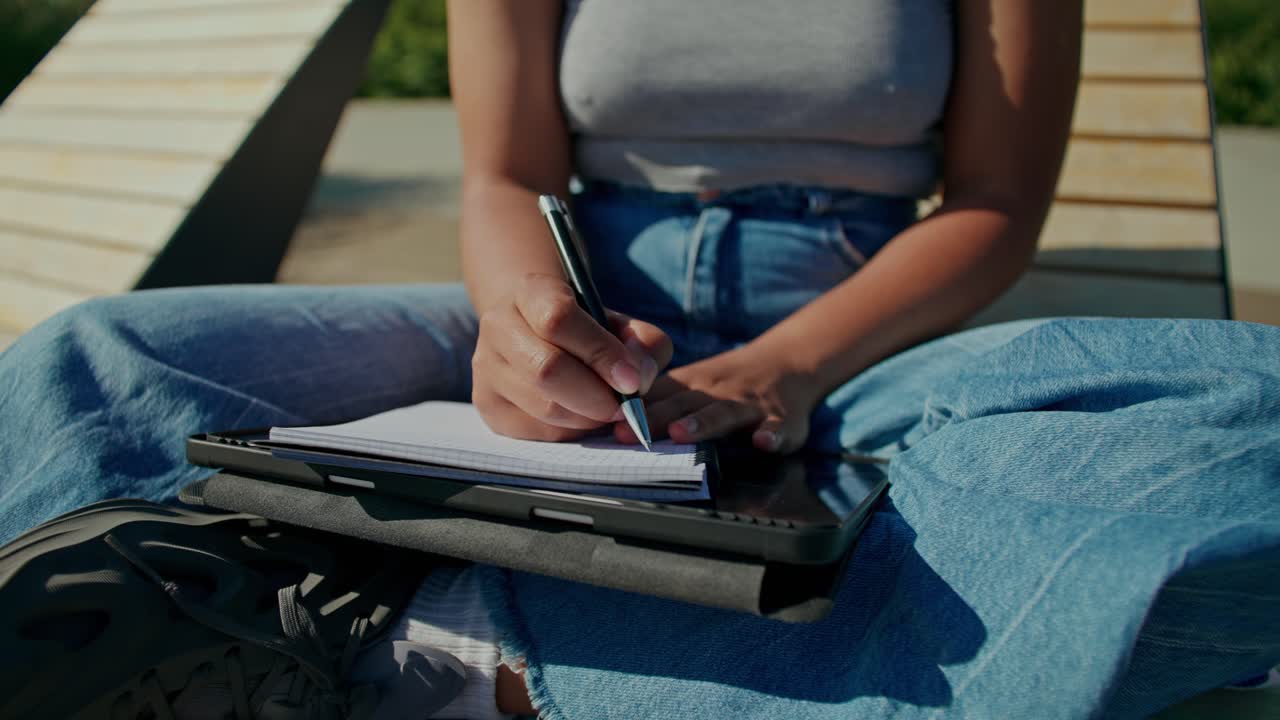 Donna che scrive in un quaderno all'aperto