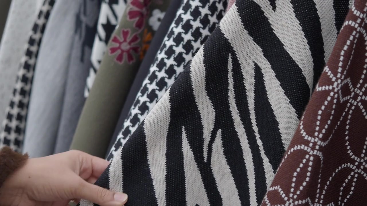 Person Touching Zebra Print Fabric on Clothing Rack