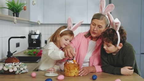 grandmother and grandchildren decorate easter bread together
