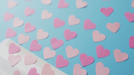 envelope with paper hearts on blue background at valentine's day