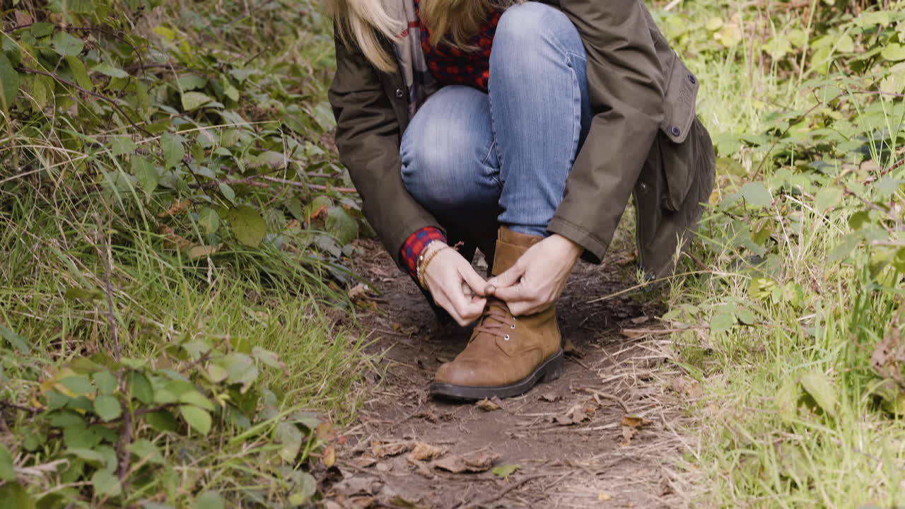 Woman tying shoelace on forest path