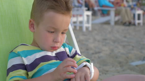 Little-boy-with-smart-watch-sitting-in-deck-chair